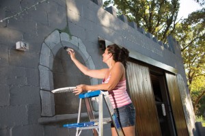 ART RETRO - Sabrina Polk, a Bridgeport artist, puts the final touches on the newest cabin at Wise County Old Settlers' Reunion. The cabin, built by Will and Keely Gage, of Paradise, mimics a medieval castle. Messenger photo by Joe Duty