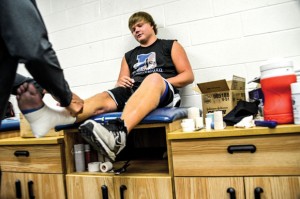 PREPARING FOR WORK - Trainer Kurt Wood wraps Tyler Story's foot and ankle before a workout Thursday. The tape, along with a brace, allows the senior to run on his right leg despite a dead nerve that keeps him from lifting his foot. Messenger photo by Joe Duty