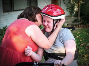 GRATEFUL FAMILY - Lanette McClure of Greenwood kisses her daughter, Jessica, after Jessica was presented a modified tricycle from Charlie Young and Bill Silver, members of the Irving chapter of AMBUCS service organization. Also on hand for the presentation was Jessica's father, Russell. "My parents spend a lot of money on my medical bills," Jessica said. "I didn't want to ask them to pay for this, too. Thank you so much." Messenger photo by Joe Duty