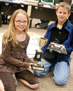 HELLO MR. ROBOTO - Lynsey Medlin (left) and Matthew Eisen pose with their team's robot and second place trophy at Monday night's board meeting. A third teammate, Kyndel Beck, was unable to attend. Messenger photo by Jimmy Alford