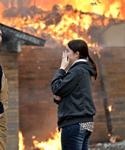 Ashly Dobyns can only watch as fire consumes her family's home Wednesday morning. Photo by Joe Duty.