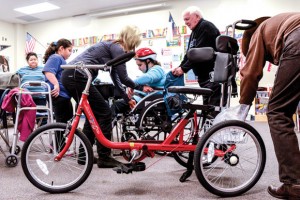 NEW SET OF WHEELS - Physical therapist Sheri Huling helps McCarroll Middle School seventh grader Aneliz Medina from her wheelchair to her new AmTryke, with the help of Bob Silver of AMBUCS, the organization that donated the tricycle. Aneliz's mother, Alma, and 10-year-old sister, Paola, are also pictured. Messenger photo by Joe Duty