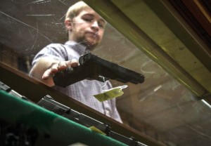 UNDER FIRE - Like many other stores, 2K Pawn and Gun Shop in Decatur has had trouble keeping ammunition on the shelves due to high demand. They've also seen an increase in people, especially women, purchasing handguns lately. Employee Ty McMaster displays a model. Messenger photo by Joe Duty