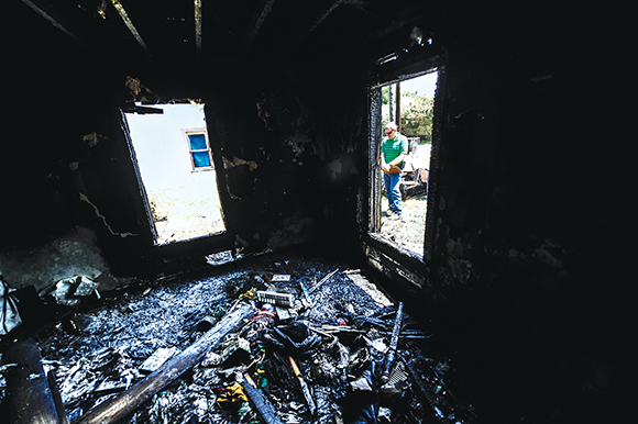 AFTERMATH - Wise County Fire Marshal Chuck Beard surveys the damage a day after a fire consumed a home in Chico. The fire started when a candle tipped over in a bedroom late Tuesday night.