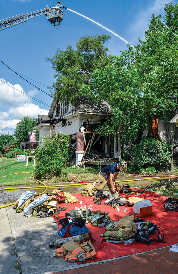 CYCLING IN — After a break, Decatur Firefighter James Carr gears up to fight a multi-family house fire at 500 W. Walnut St. in Decatur Monday. Wise County EMS set up a firefighter rehabilitation center near the scene.