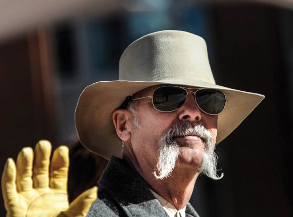 WESTERN STYLE - A horseback rider sporting a handlebar mustache waves to the crowd on the streets of downtown Fort Worth Saturday. Messenger photo by Joe Duty